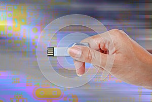 Hand holding USB data storage against light and circuit