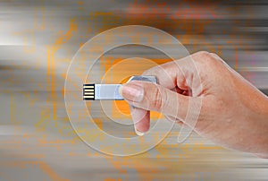 Hand holding USB data storage against light and circuit