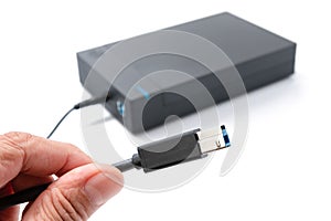 Hand holding USB plug, cable for external hard drive casing isolated