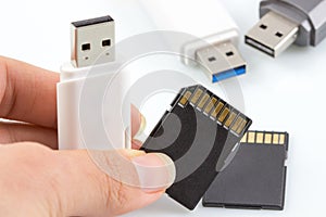 Hand holding usb stick, usb flash drive and memory card on white background