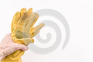 hand holding a used pair of yellow leather working gloves