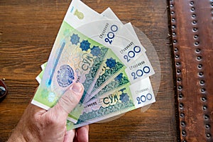 Hand holding Uzbekistani money, known as So`m