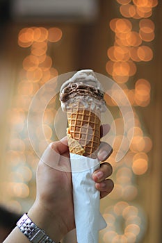 A hand holding vanilla and chocolate ice cream or gellato on a cone