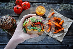 Hand holding vegan sweet potato black bean burger. Plant based food concept photo