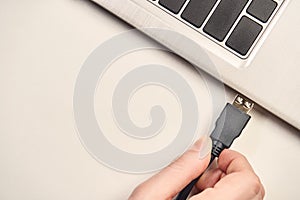 Hand holding video cable connector for plug to laptop