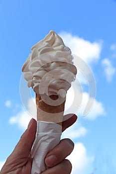 Hand holding waffle cone with twisted ice cream