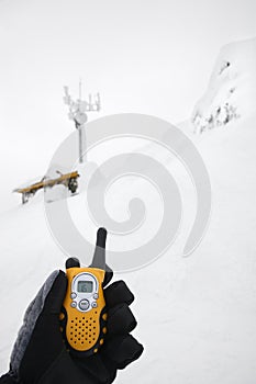 Hand holding walkie talkie in snow.