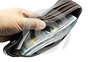 Hand holding wallet on bundles of 100 US dollars banknotes