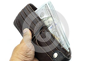 Hand holding wallet on bundles of 100 US dollars banknotes