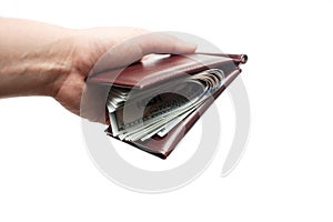 A hand holding a wallet full of new one hundred dollar bills isolated over a white background. Copy space