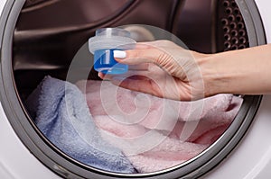 Hand holding washing gel in drum of washing machine