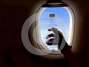 Hand holding water bottle near the aircraft window
