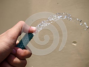 Hand holding a water hose with water coming out