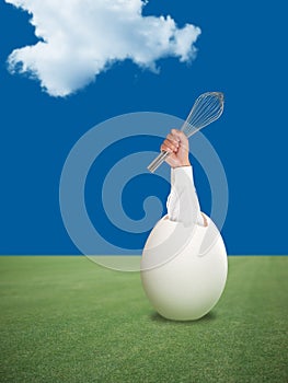 Hand holding a whisk inside an egg