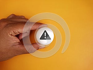 Hand holding white ball table tennis with icon alert on background