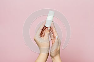 Hand holding white bottle. Drops for eye, nose or ear in hand on pink background. Pharmaceutical product