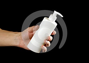 Hand holding a white bottle of liquid soap. Close up. Isolated on black background