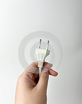 Hand holding white cable plug