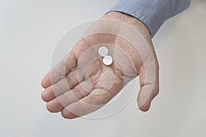 Hand is holding white capsules on white background. Top view. Copy space, high resolution product.