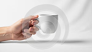 A hand holding a white ceramic mug against a plain white background