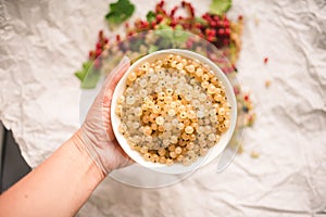 Hand holding white currant berries in a bowl