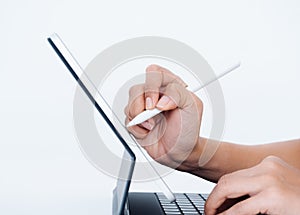 Hand holding white electronic pen or pencil, writing or drawing on digital tablet screen.