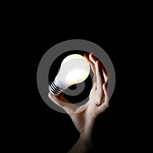 Hand holding white light bulb on balck background