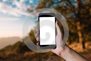 Hand holding white mobile phone with blank white screen.