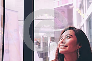 Hand holding white mobile phone with blank white screen and blur smiley woman face background in modern cafe