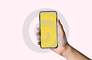 Hand holding white mobile phone with blank yellow screen.