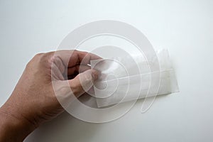 Hand holding a white package of disposable shower cap against white background