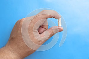 Hand holding white pill on blue background, great design for any purposes. Health care medical background.