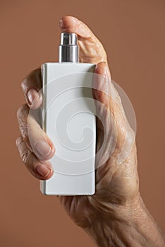 Hand holding a white refillable spray bottle