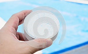 Hand holding a white rounded chlorine tablet. photo