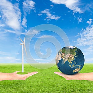 Hand holding wind turbine and earth