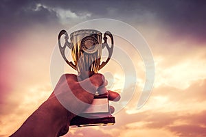 Hand holding winner trophy