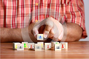 Hand holding wood block with group of people icon , wood block with group of people icon on wood floor