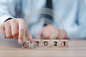 Hand holding wood cubes with New year 2021 and goal or target icon. concept of New year Business goals and vision