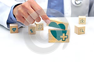 Hand holding a wooden block with healthcare medical symbol, heart rate icon and around is a wooden block with blurred icon symbol.