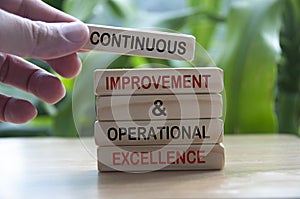 Hand holding wooden blocks with text - Continuous improvement and operational excellence.