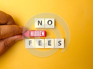 Hand holding wooden clips with the word NO HIDDEN FEES on yellow background.Business concept.