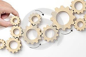 Hand holding wooden cog flowing process management on white background