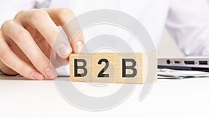 hand holding wooden cube with B2B text on table background. financial, marketing and business concepts