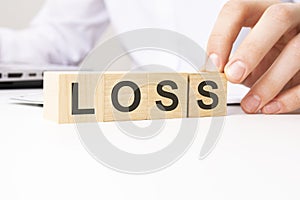 hand holding wooden cube with LOSS text on table background. financial, marketing and business concepts