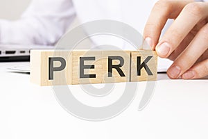 hand holding wooden cube with PERK text on table background. financial, marketing and business concepts