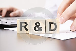 hand holding wooden cube with R and D text on table background. financial, marketing and business concepts