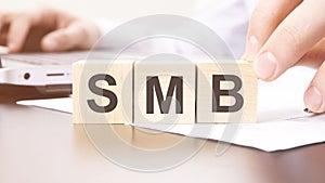 hand holding wooden cube with SMB text on table background. financial, marketing and business concepts