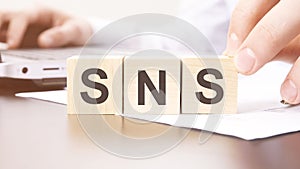 hand holding wooden cube with SNS text on table background. financial, marketing and business concepts