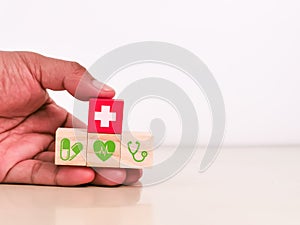 Hand holding wooden cubes with health care icons.