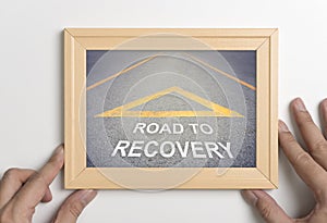 Hand holding wooden frame with road to recovery concept photo